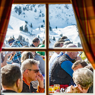 Ausblick aus dem Fenster auf Personen vor der Mankei Alm in Obertauern