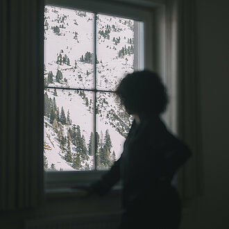 Frau schaut aus dem Fenster im Hotel Enzian in Obertauern 