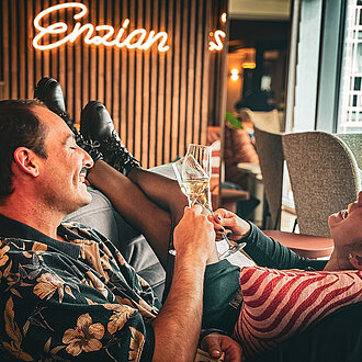 glückliche, lachende Gäste mit einem Drink in der Hotellounge im Hotel Enzian in Obertauern 