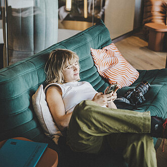 auf der Couch sitzende Dame im Loungebereich des Hotel Enzian in Obertauern 