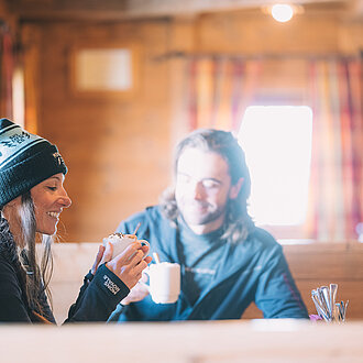 Paar genießt ein heißes Getränk in der Mankei Alm in Obertauern