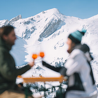 Paar genießt Aperol vor der Mankei Alm in Obertauern