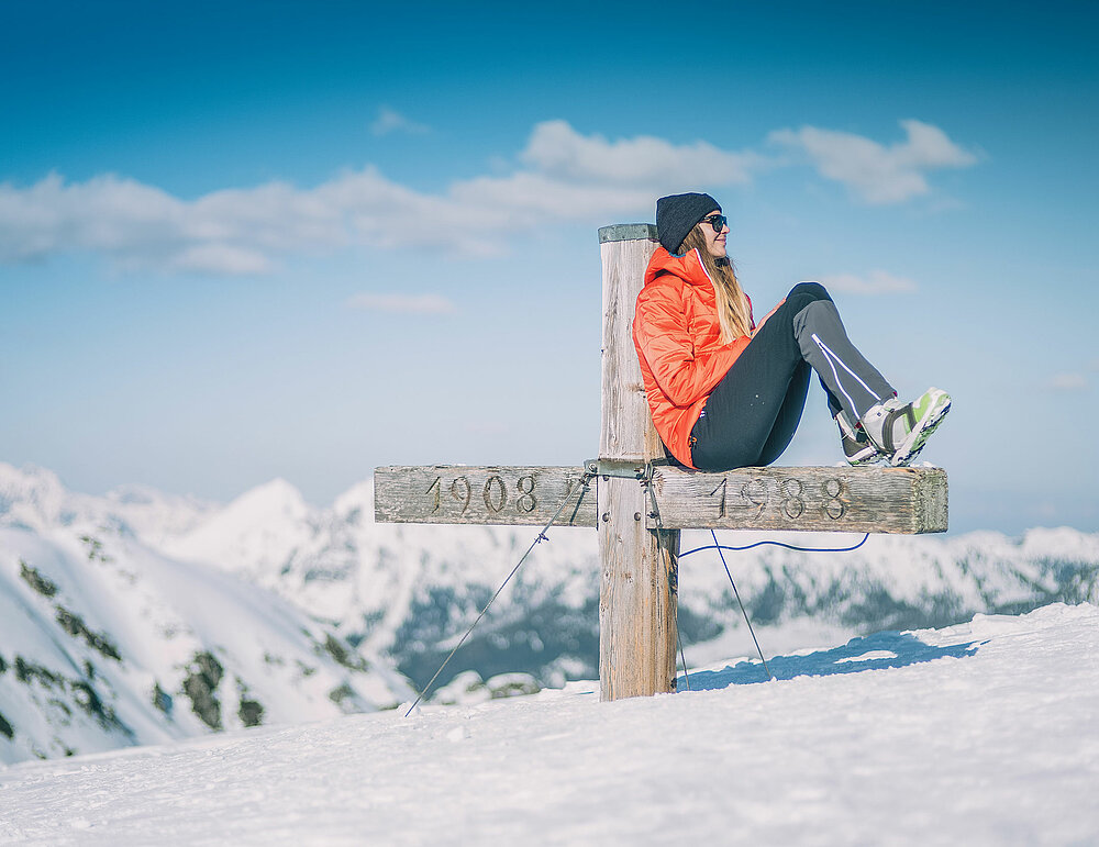 woman at at snowy mountain cross in the winter in obertauern 